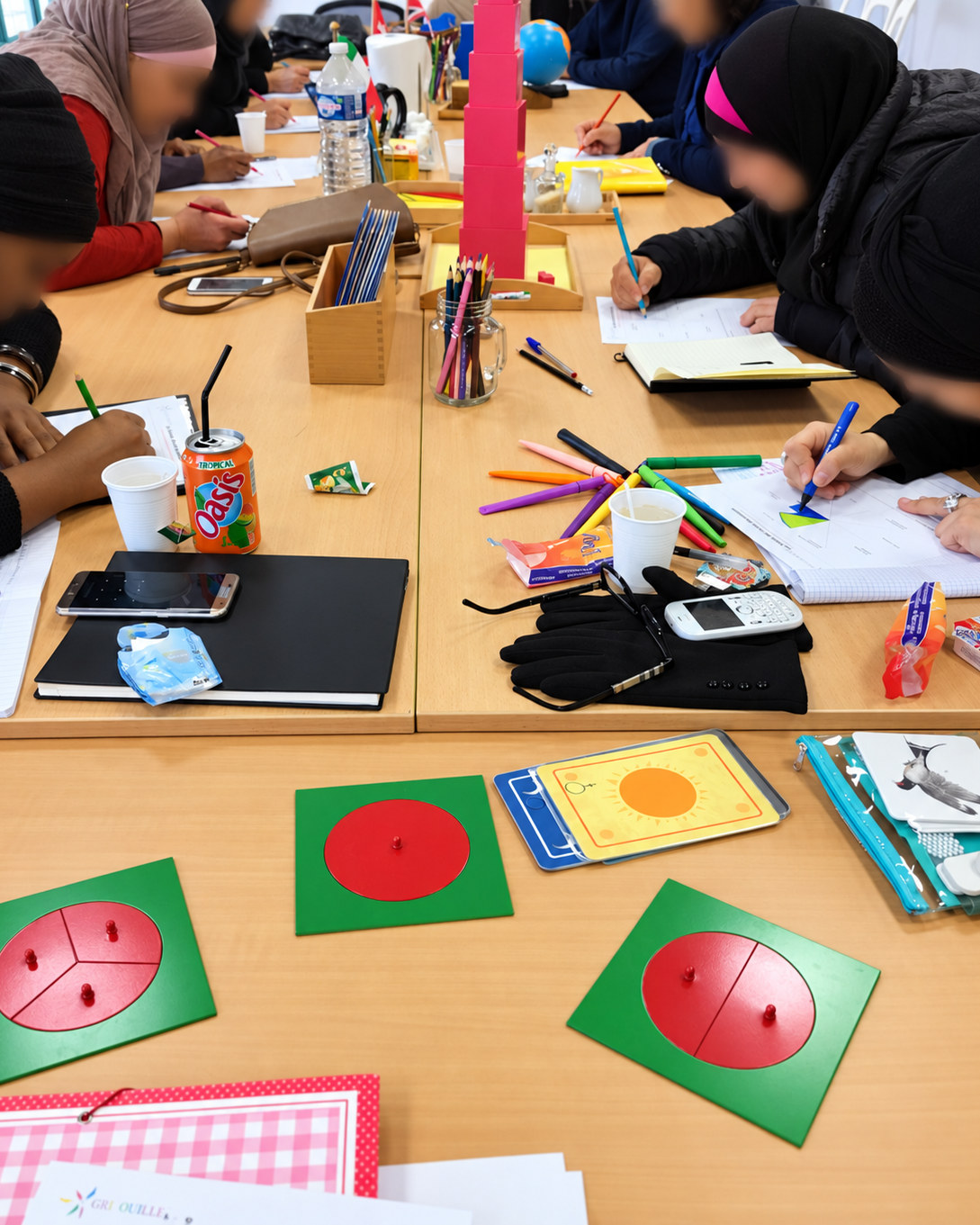 Un atelier Gribouille : des mamans au travail autour de la tour rose et des encastrements de fractions
