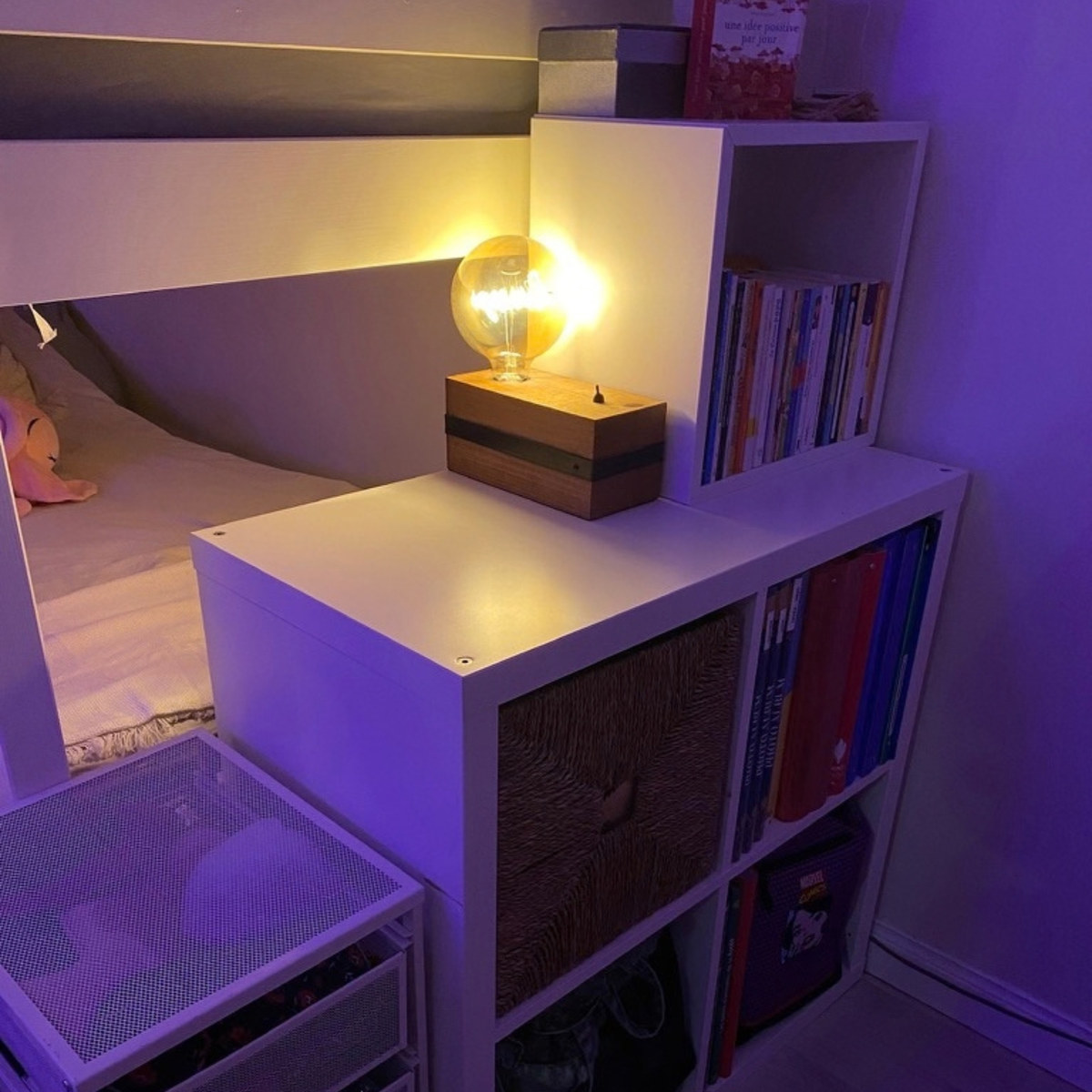 Le coin du soir : une petite lampe allumée près du lit et les livres rangés