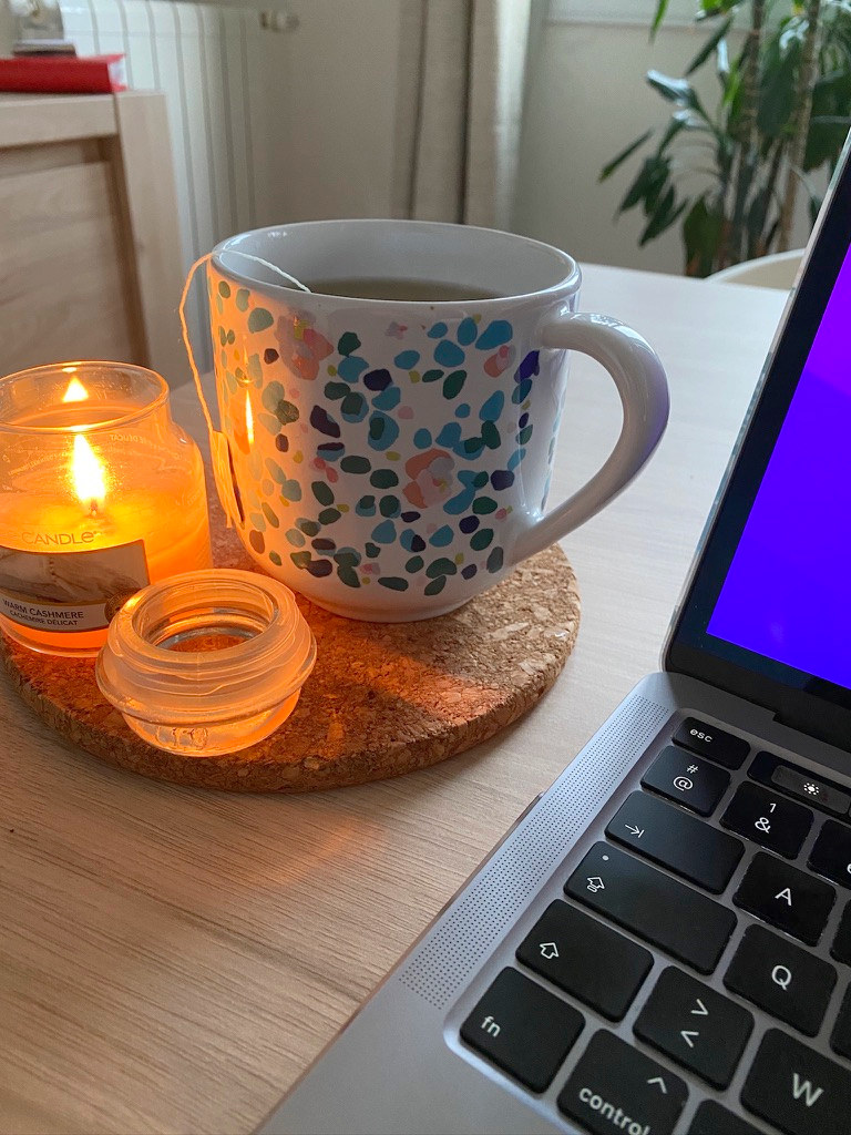 Une tasse de thé et une bougie allumée près de l'ordinateur
