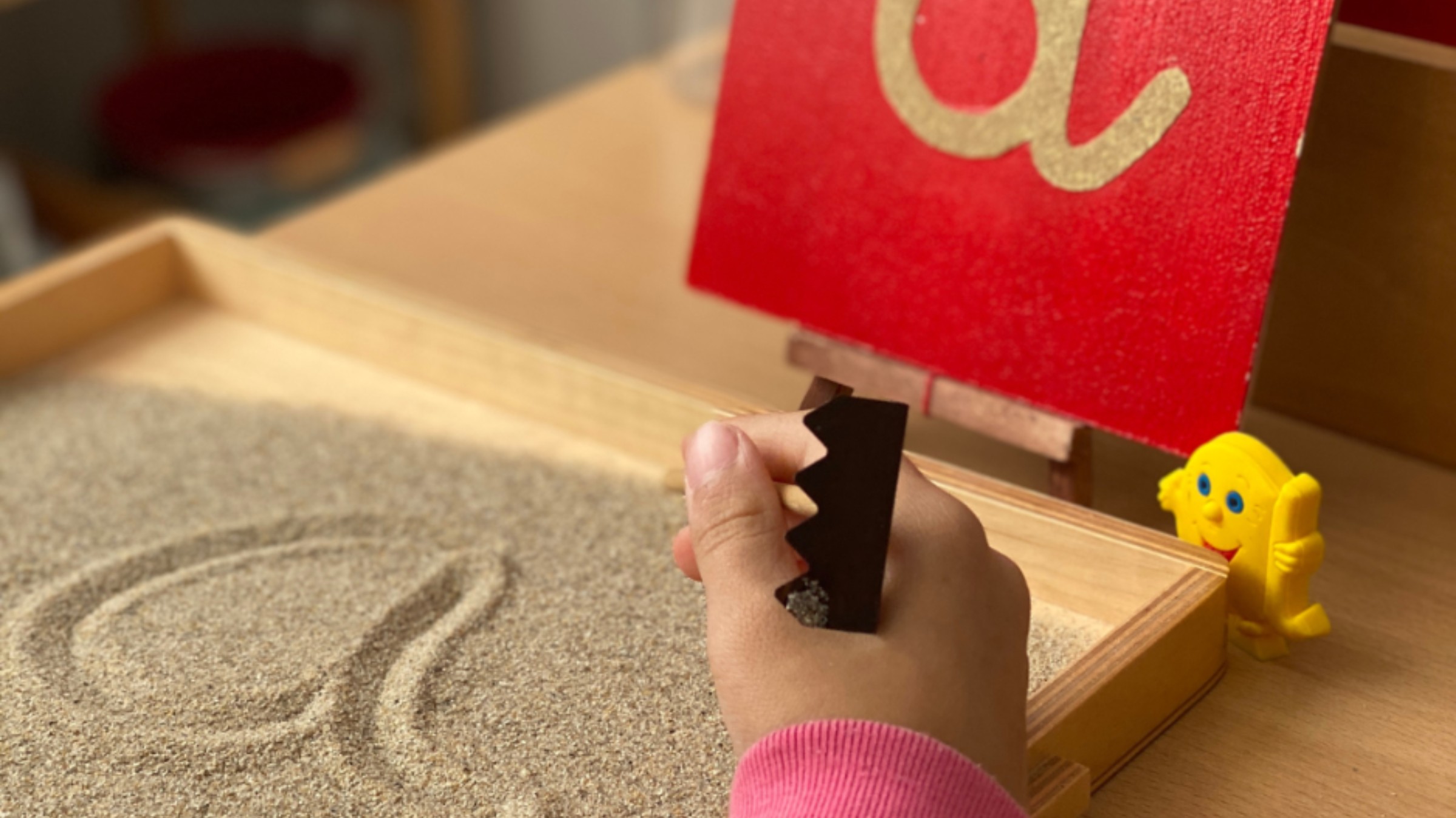 Un enfant qui trace une lettre dans le sable